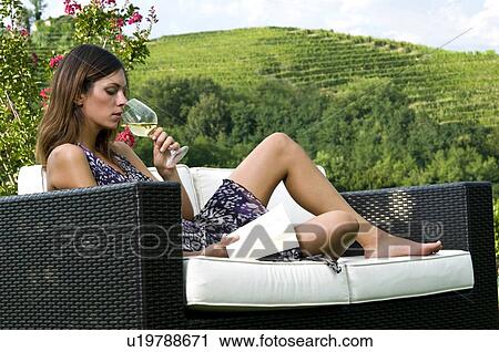 Young woman sitting on couch in vineyard with white wine reading a book View Large Photo Image Stock Image - Young woman sitting on couch in vineyard with white wine reading a book. Fotosearch