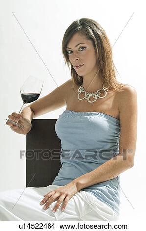 Picture - Young woman sitting with glass of red wine. Fotosearch
