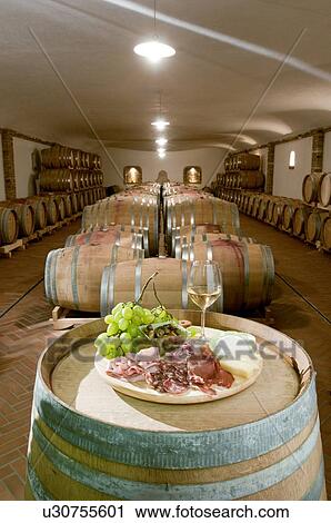 Antipasti platter and glass of white wine with barrels of wine in a cellar View Large Photo Image Stock Image - Antipasti platter and glass of white wine with barrels of wine in a cellar. Fotosearch