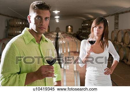Stock Photography - Couple in a wine cellar with glasses of red wine. Fotosearch