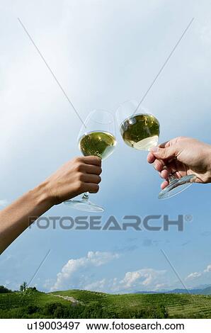 Young woman's and young man's hands holding wineglasses with white wine and toasting View Large Photo Image Stock Photo - Young woman's and young man's hands holding wineglasses with white wine and toasting. Fotosearch