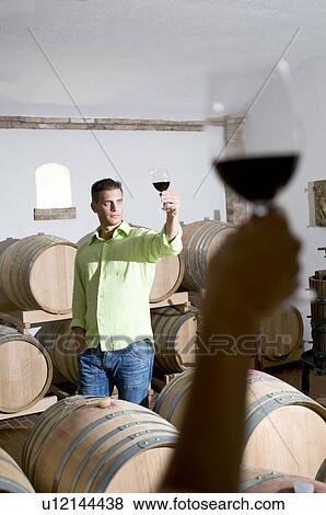 Young woman's hand holding glass of red wine with young man in background holding up his wineglass View Large Photo Image Stock Photo - Young woman's hand holding glass of red wine with young man in background holding up his wineglass. Fotosearch