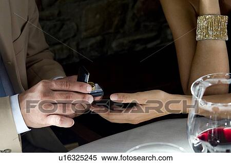 Stock Photography - Closeup of hands of young man giving a ring to young woman. Fotosearch