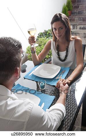 Stock Image - Couple sitting at table drinking white wine. Fotosearch