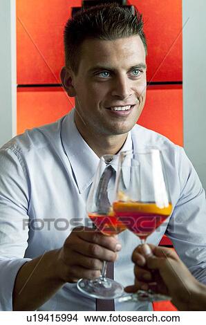 Picture - Young man and young woman's hand toasting with glass of orange wine . Fotosearch