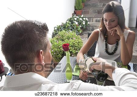 Young man pouring wine for young woman at restaurant table View Large Photo Image Stock Photo - Young man pouring wine for young woman at restaurant table. Fotosearch