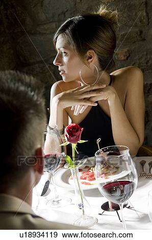 Stock Photo - Young woman sitting at restaurant table with young man. Fotosearch