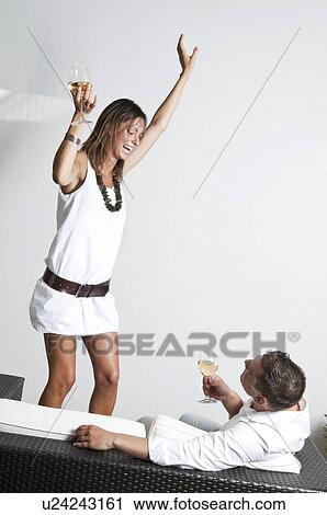 Young woman with white wine dancing next to couch with young man and wine View Large Photo Image Stock Image - Young woman with white wine dancing next to couch with young man and wine. Fotosearch