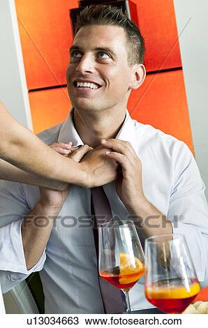 Stock Image - Young woman's arms adjusting young man's tie. Fotosearch