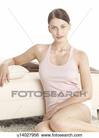 Stock Photograph - Dark-red haired woman in underwear sitting on the floor. Fotosearch