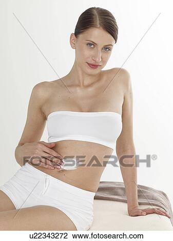 Stock Image - Woman creaming her belly. Fotosearch