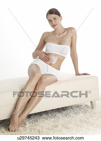 Stock Image - Woman creaming her belly. Fotosearch