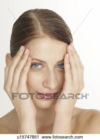 Stock Image - Woman is putting hands on her face. Fotosearch