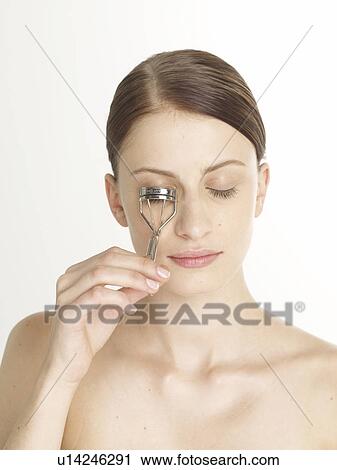 Stock Image - Woman with an eye lash curler. Fotosearch