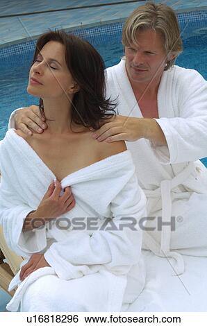 Stock Photograph - Couple at the swimming pool - man is massaging woman. Fotosearch