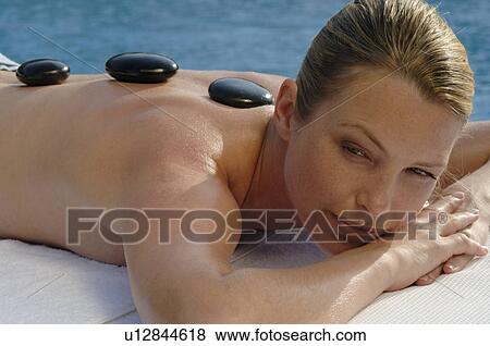 Stock Photo - Hot stone massage - woman on the massagebed. Fotosearch