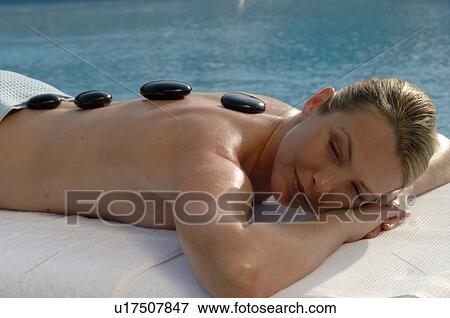 Stock Photo - Hot stone massage - woman on the massagebed. Fotosearch