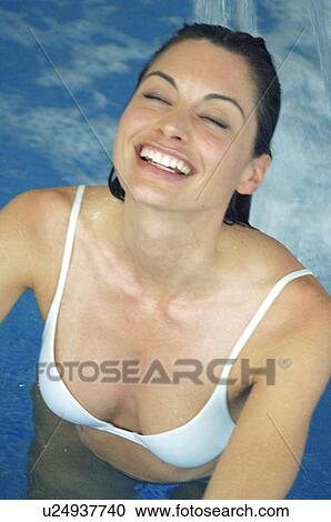 Stock Image - Woman in the swimming pool unter a shower. Fotosearch