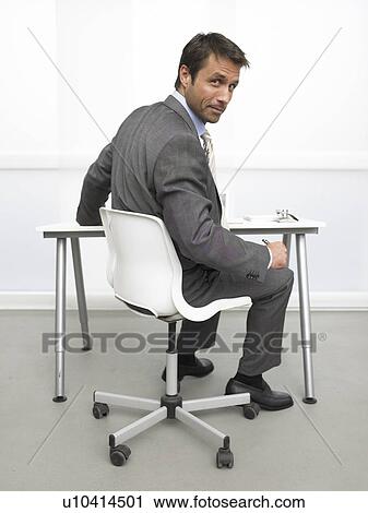 Business man at his desk is looking back View Large Photo Image Stock Image - Business man at his desk is looking back. Fotosearch