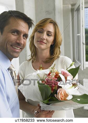 Stock Image - Business man is giving a bouquet to business woman. Fotosearch
