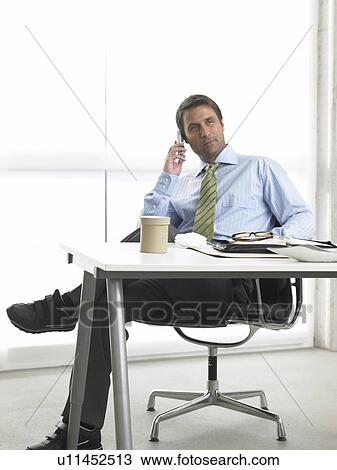 Business man is making a phone call at his desk View Large Photo Image Stock Image - Business man is making a phone call at his desk. Fotosearch