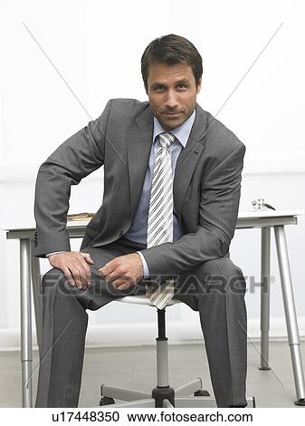 Stock Image - Business man sitting in front of his desk. Fotosearch