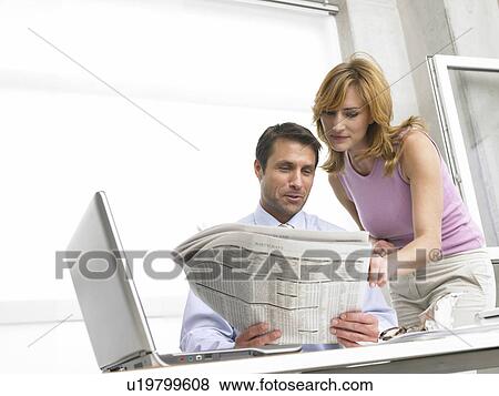 Stock Photo - Business woman and man are reading the newspaper. Fotosearch