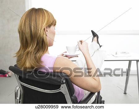 Business woman is drinking coffee at her desk View Large Photo Image Stock Photo - Business woman is drinking coffee at her desk. Fotosearch