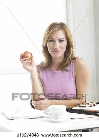 Stock Photo - Business woman is eating an apple. Fotosearch