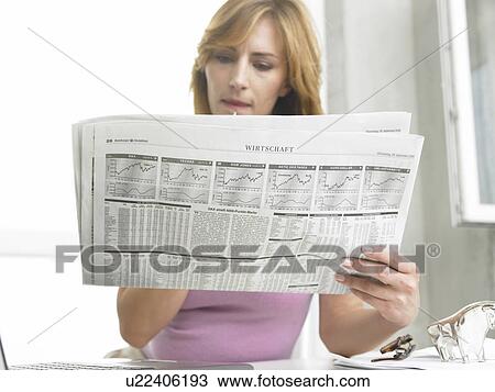 Stock Image - Business woman is reading the newspaper. Fotosearch