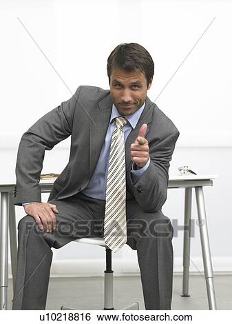Sitting business pointing with his finger View Large Photo Image Stock Photograph - Sitting business pointing with his finger. Fotosearch