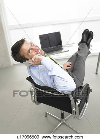 Telephoning business man having his legs on his desk View Large Photo Image Stock Photo - Telephoning business man having his legs on his desk. Fotosearch