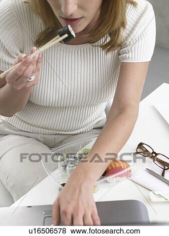 Woman is eating sushi at her desk View Large Photo Image Stock Photo - Woman is eating sushi at her desk. Fotosearch