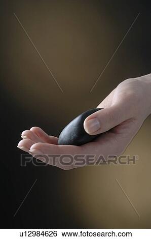 Stock Photograph - Hand is holding a black stone. Fotosearch