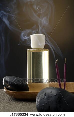 Picture - Joss sticks, black stones and a cosmetic bottle. Fotosearch
