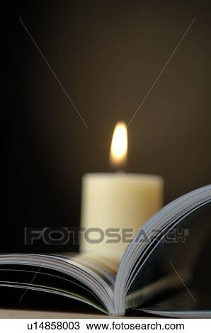 Stock Image - Open book with a candle. Fotosearch