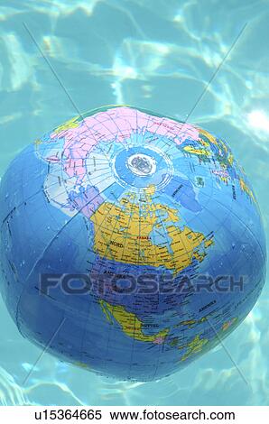 Stock Photography - Globe beach ball swimming in the water. Fotosearch