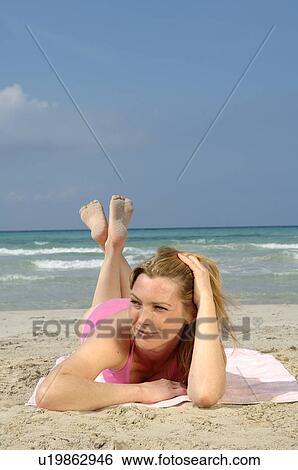Stock Photograph - Woman is lying on the beach. Fotosearch