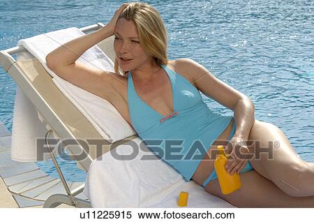 Stock Photography - Woman with sun lotion at the swimming pool. Fotosearch