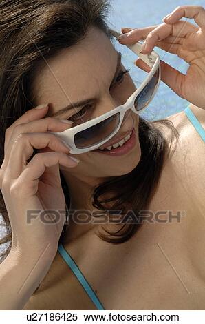 Stock Photography - Woman with sunglasses next to the swimming pool. Fotosearch