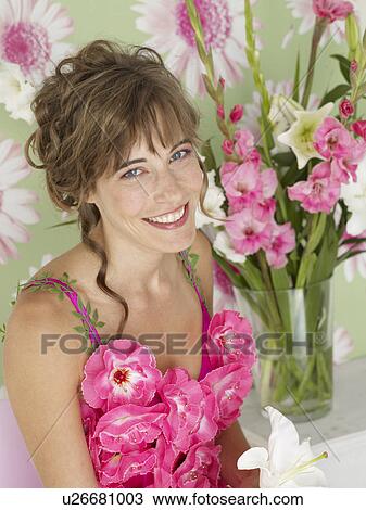 Stock Image - Woman in front of a flowery wallpaper. Fotosearch