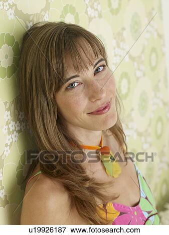 Woman wearing a flowery dress is sitting in front of a flowery wallpaper View Large Photo Image Stock Photo - Woman wearing a flowery dress is sitting in front of a flowery wallpaper. Fotosearch