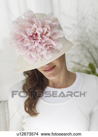 Woman wearing a hat with a pink blossom View Large Photo Image Picture - Woman wearing a hat with a pink blossom. Fotosearch