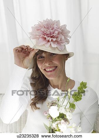 Woman wearing a hat with a pink blossom View Large Photo Image Stock Photo - Woman wearing a hat with a pink blossom. Fotosearch