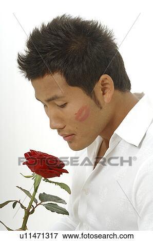 Stock Photo - Asian man with a red rose and a kissmouth on his check. Fotosearch