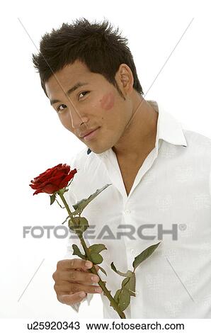 Stock Image - Asian man with a red rose and kissmouth on his check. Fotosearch