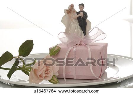 Picture - Happy couple, a pink rose and a gift on the plate. Fotosearch