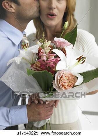 Stock Photography - Man kissing woman with a bouquet. Fotosearch