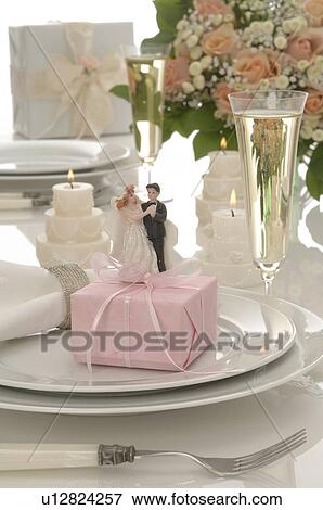 Stock Photo - Wedding desk with a happy couple, a gift, sparkling wine, candles and a bouquet. Fotosearch