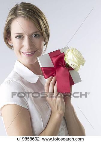 Stock Image - Woman with a gift and white rose blossom. Fotosearch